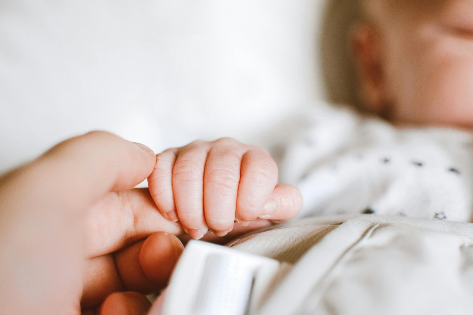 A parent holding a newborn’s fingers